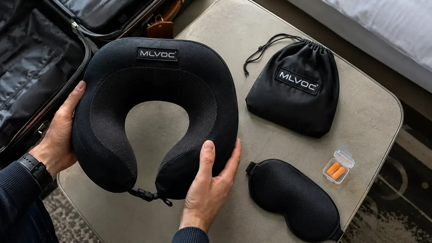 Travel sleep kit laid out flat: neck pillow, eye mask, earplugs, and a small travel bag